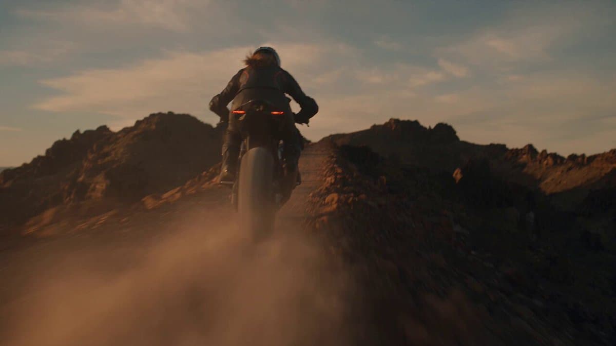 A confident woman in her mid-20s wearing a fitted matte-black motorcycle racing 